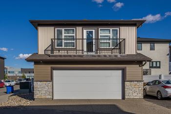 A modern house with a garage door and a balcony.